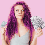 woman with curly pink hair looking unsure holding a credit card and money in her hands