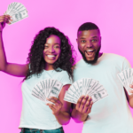 happy black couple smiling and holding hundred dollar bills,