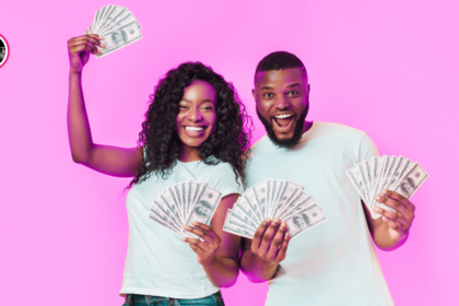 happy black couple smiling and holding hundred dollar bills,